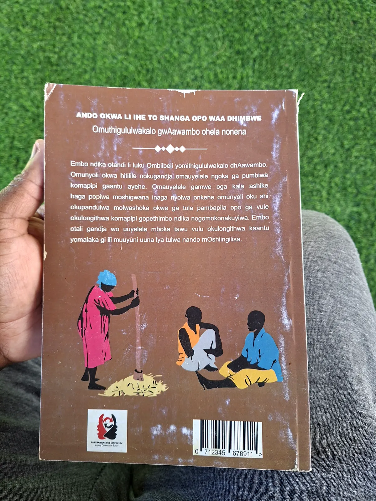 Back cover: title, a short description in Oshiwambo, and an illustration of a woman pounding grain beside two seated men.